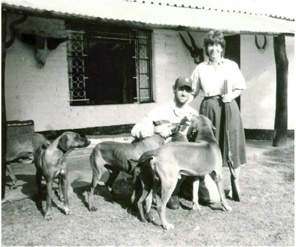Two people and several dogs outside a house